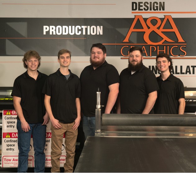 A&A Graphics Team. Five well dressed men standing in front of sign
